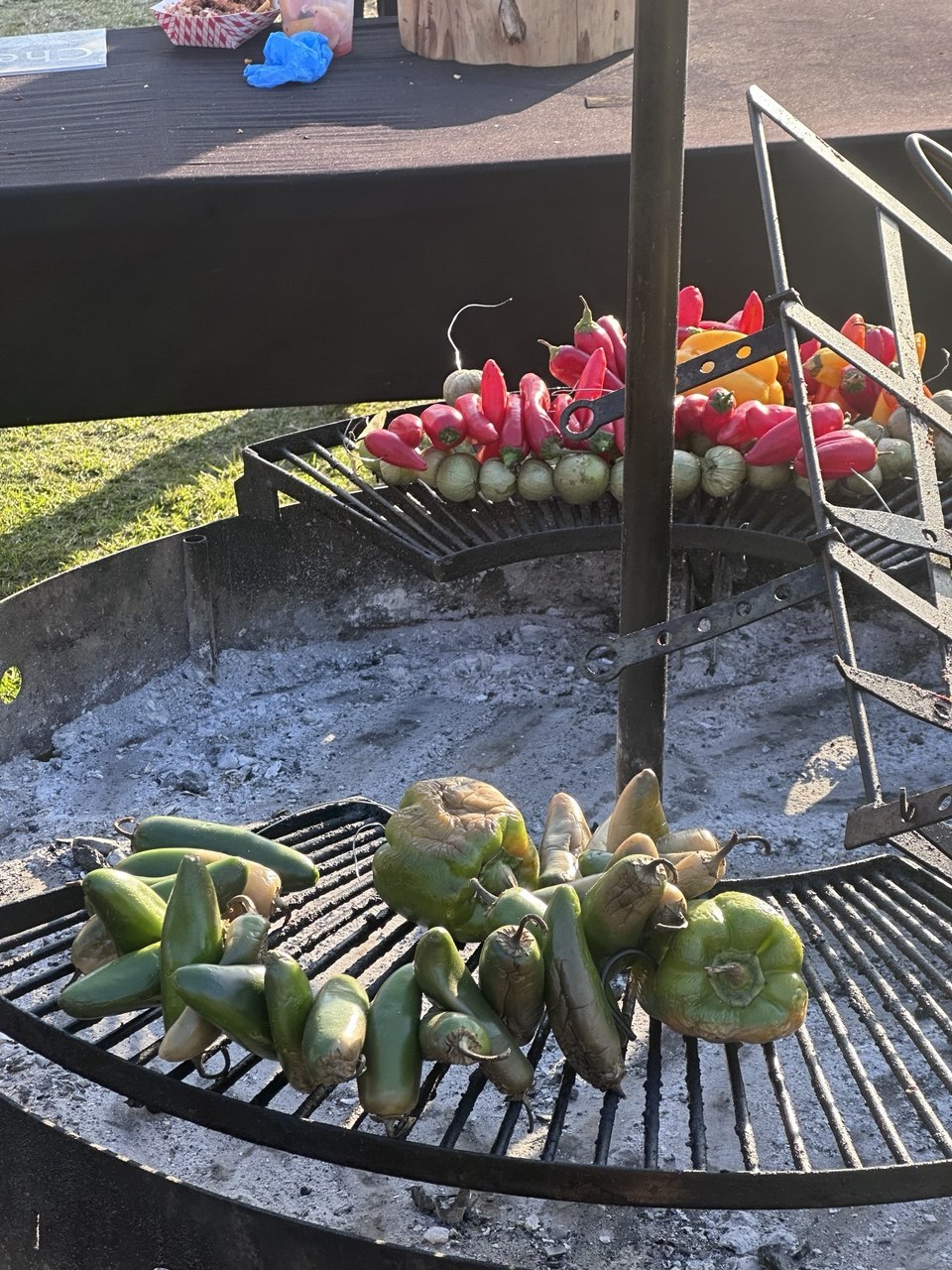 Fresh peppers and tomatillos charring over coals on the Go Hard Grills grill