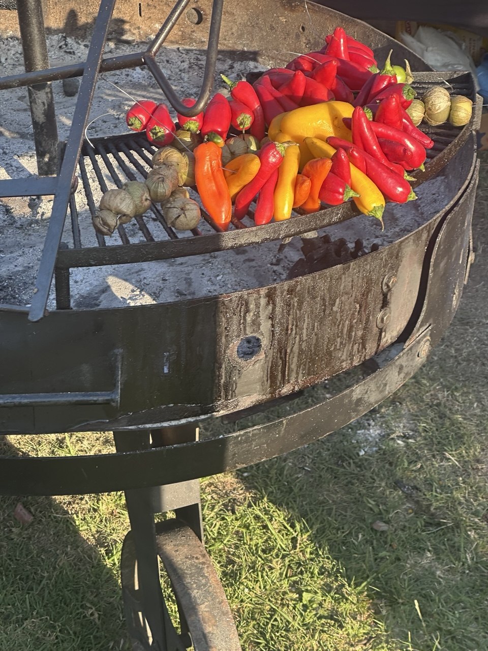 Colorful peppers and tomatillos roasting on the Go Hard Grills open pit